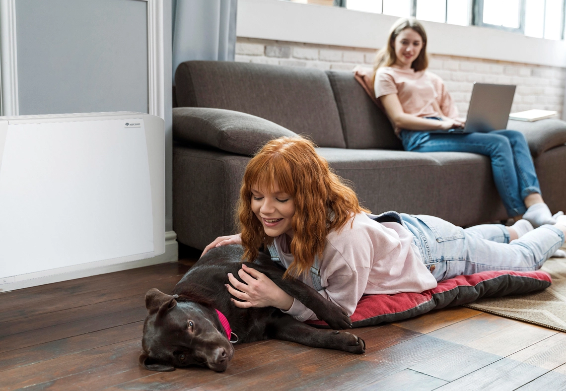 MyCond SEC/F Ein Mädchen und ihr Hund neben einem Gebläsekonvektor.